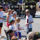 Kids pick up candy and wave at parade participants. 
