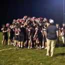 After the big win, the players raise their helmets in a huddle.