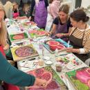 A table of artists paint pomegranates on silk