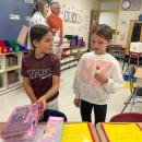 Reagan Tracy, left, and Mikey Waterman, both 8, chat and unpack school supplies. 