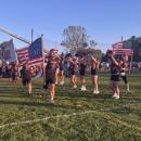 The football team runs through a banner amid rows of cheerleaders as they enter the field before the game.