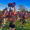 Cheerleaders welcome the football team onto the field before the game.