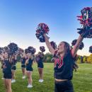 Libby Achilles cheers with pom poms held high.