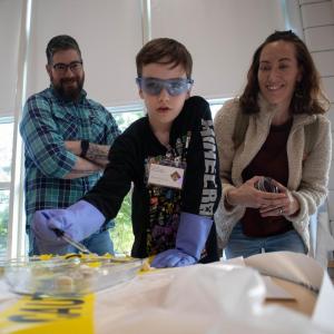 Henry Bishop, center, carefully drops hydrochloric acid onto rocks to test which sample is limestone while parents Jarod Bishop and Gillian Bishop look on. Photos by: Sawyer Smook-Pollitt