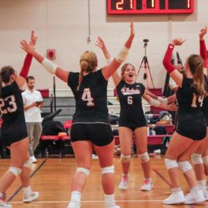 Old Rochester varsity volleyball players celebrate after scoring a point.