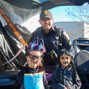 Sergeant Sean Day with Lexie Dupont age 5, dressed as a magical vampire bat, and Hazel Moore age 5, dressed as Wednesday Addams. Photos by Mari Huglin  Sergeant Sean Day with Lexie Dupont, dressed as a magical vampire bat, and Hazel Moore, dressed as Wednesday Addams. Photos by Mari Huglin