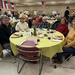 Friends and the community smile together at shared tables.