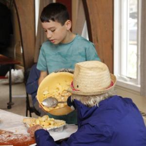 Two volunteers fill a pie crust with filling.