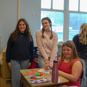 Bridget Coryer and Libby Achilles smile with a student.