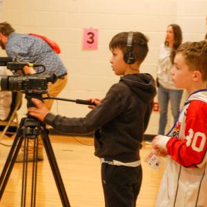 Some students practice broadcast journalism skills during the assembly.