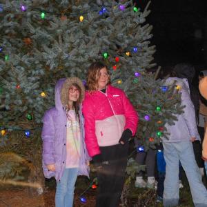 Kids pose in front of the lit tree.