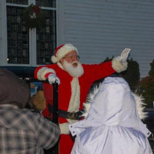 Santa arrives in a classic automobile to bring Christmas cheer.