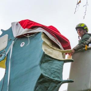 G. Bourne Knowles used his landscaping equipment to reach the top of the statue and install the new hat Dec. 6.  Photos by Grace Roche