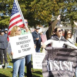 Emily Nugent of Mattapoisett holds a poster encouraging attendees to "Protect Democracy" while Avery Nugent holds a "Resist" flag at the Mattapoisett "No Kings" protest on Saturday, Oct. 18. Photo by Grace Ann Natanawan