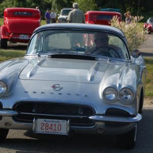 A man sits in his blue Corvette. 