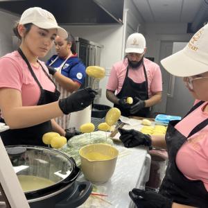 Bakery employees dip mango-flavored pastries in white chocolate. 