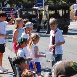 Kids pick up candy and wave at parade participants. 