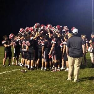 After the big win, the players raise their helmets in a huddle.