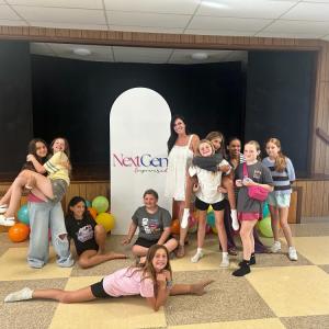 The group smiles near the community center's stage. 