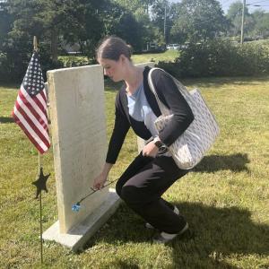 Madison Cable lays a carnation at the grave of a Revolutionary War soldier, honored at the ceremony after 250 years. Cable sang “The Star-Spangled Banner” and “God Bless America” for the ceremony.