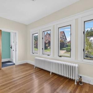 Unit 1 front room with a row of windows, a radiator and hardwood floors at 370 Maple Street, New Bedford