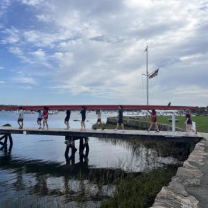 The team of eight boys, plus a coxswain, walks a boat to the waters of Sippican Harbor. Photo by Grace Roche