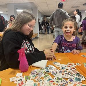 Annika Lund, left, applies a temporary tattoo on 5-year-old Scout Elder's hand. 