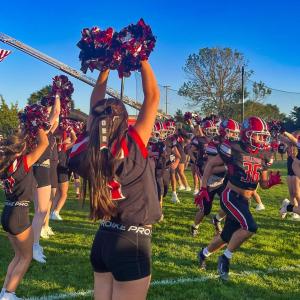 Cheerleaders welcome the football team onto the field before the game.