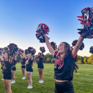 Libby Achilles cheers with pom poms held high.