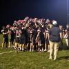 After the big win, the players raise their helmets in a huddle.